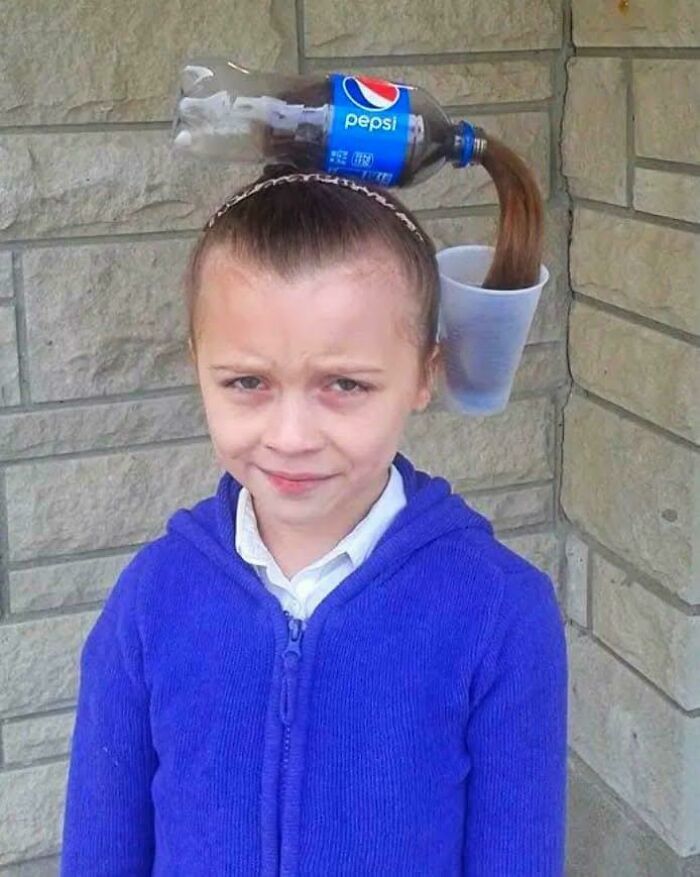 Girl with hair styled to look like Pepsi pouring from bottle into cup, a weird and confusing cursed image.