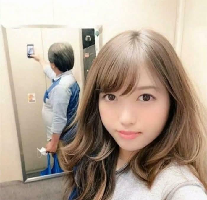 A confusing selfie in a mirror where the reflection appears to show a different person behind the woman, creating a weird optical illusion.