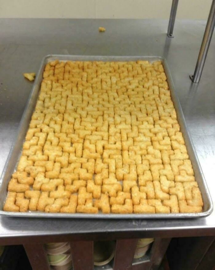 Tray of weird, confusing, and cursed shaped snacks closely packed in a kitchen setting on a metal surface.