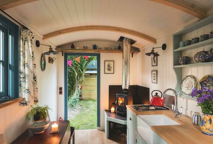 Interior of cozy small home with wood stove, kitchen sink, and decorative dishes