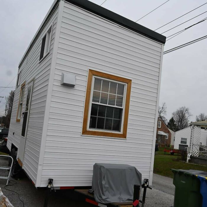 White tiny house on wheels parked in neighborhood
