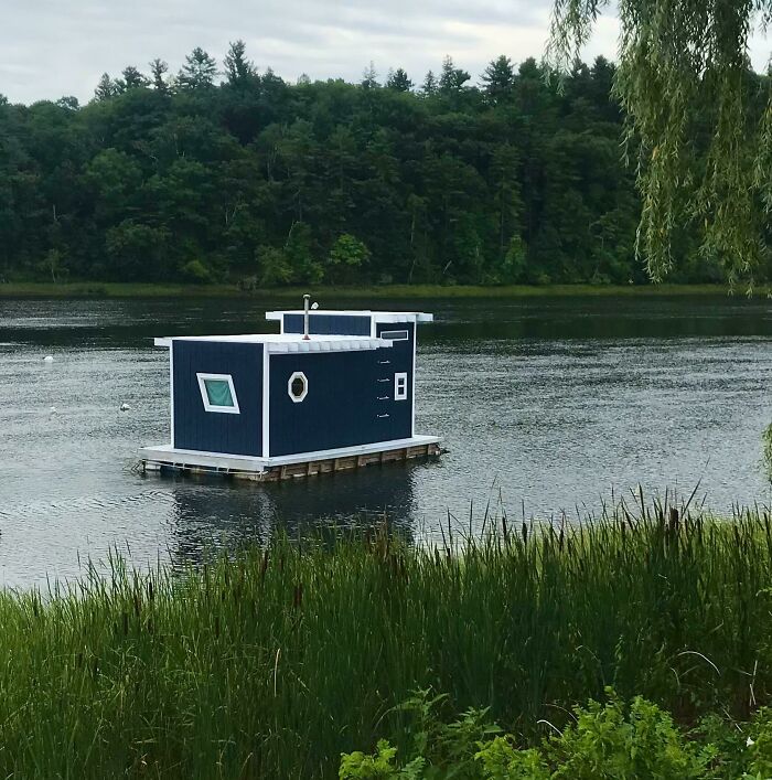 Small floating house on lake surrounded by nature