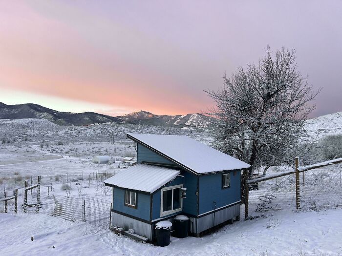 Blue small home covered with snow in rural mountainous landscape