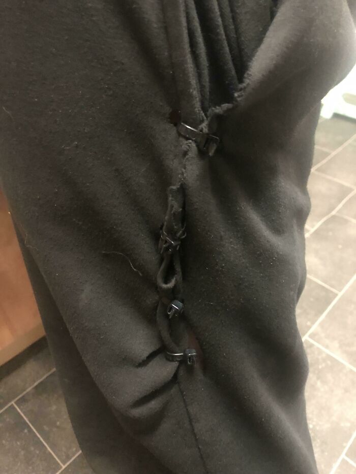 Black pants held together with black zip ties as a technically works funny solution to a ripped fabric problem.
