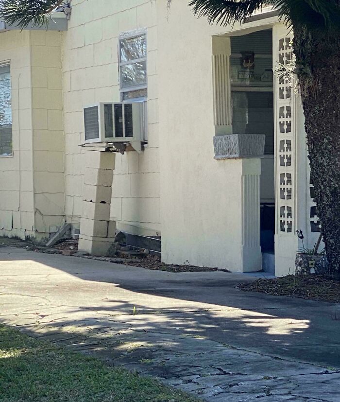 Improvised air conditioner support made from stacked concrete blocks under a window unit, a technically works solution.