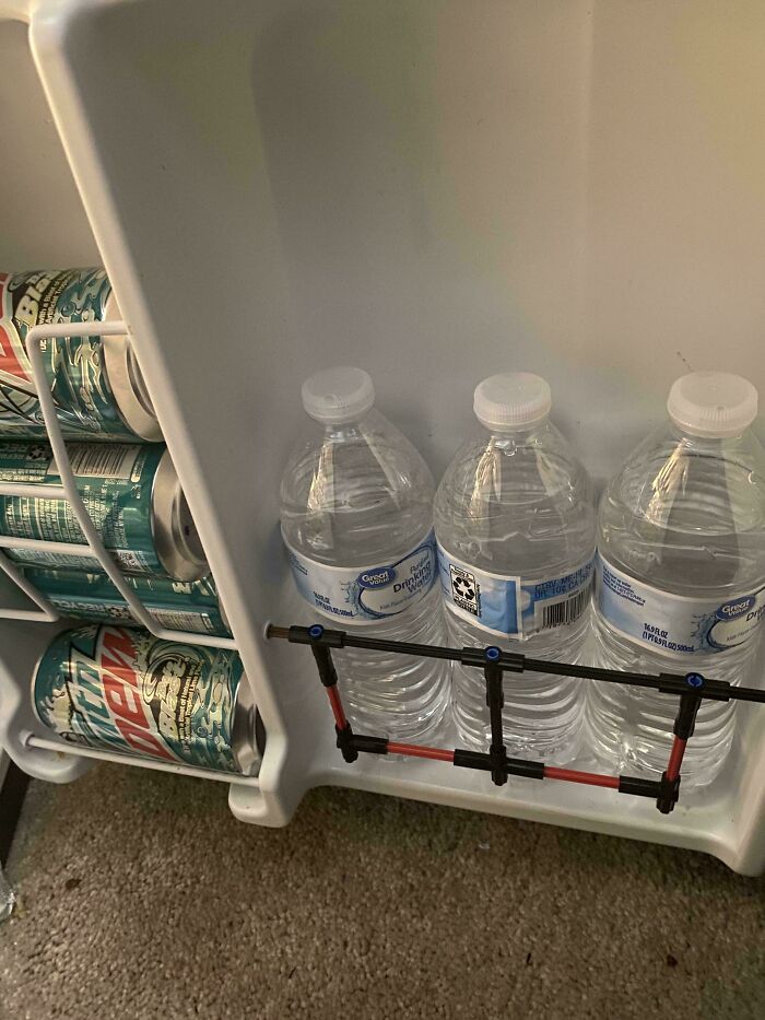 Water bottles held in place by a homemade barrier made of LEGO pieces inside a fridge door, technically works solution.