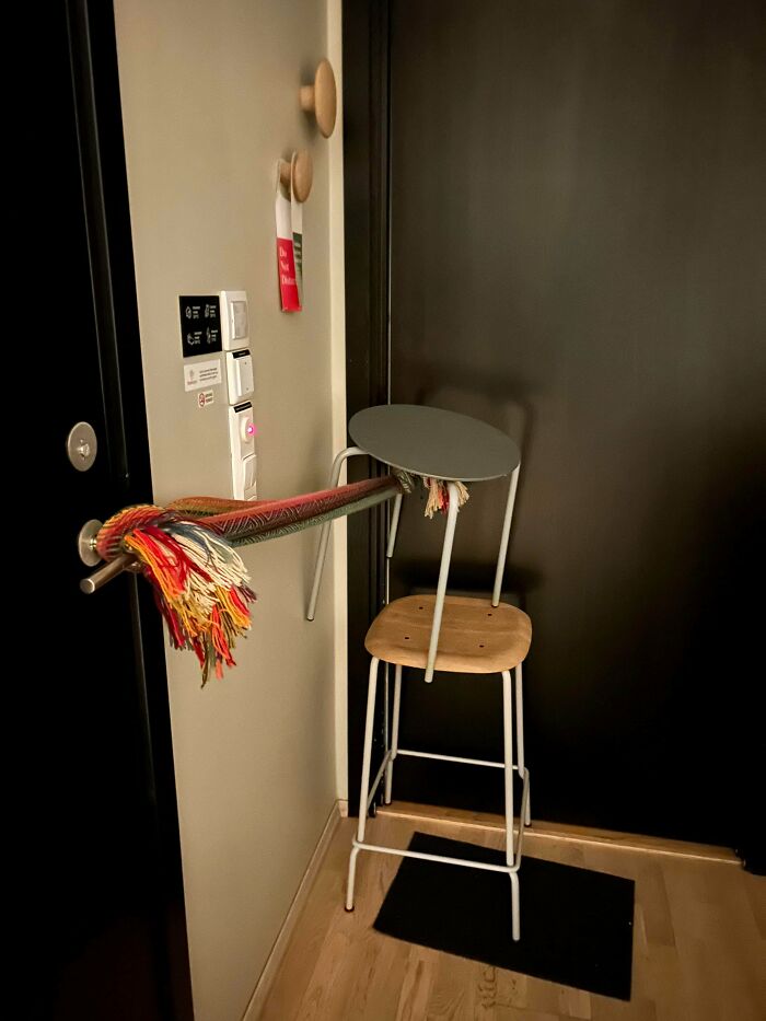 A chair tied with a colorful rug tied to a door handle as a makeshift doorstop, a technically works solution.