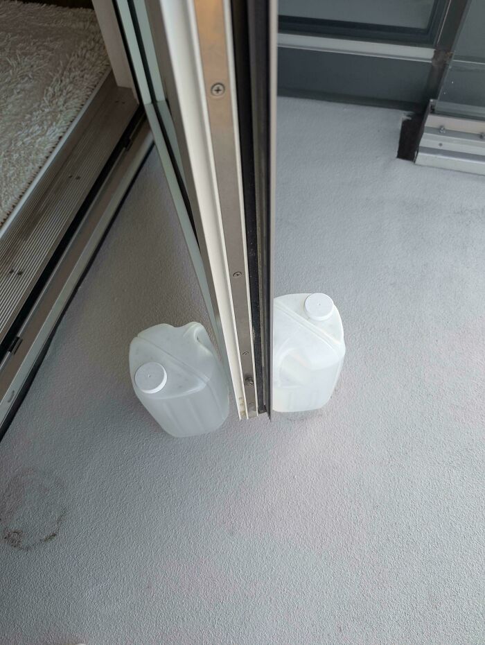 Plastic jug placed to keep a sliding door open, a technically works but hilariously dumb solution to a problem.
