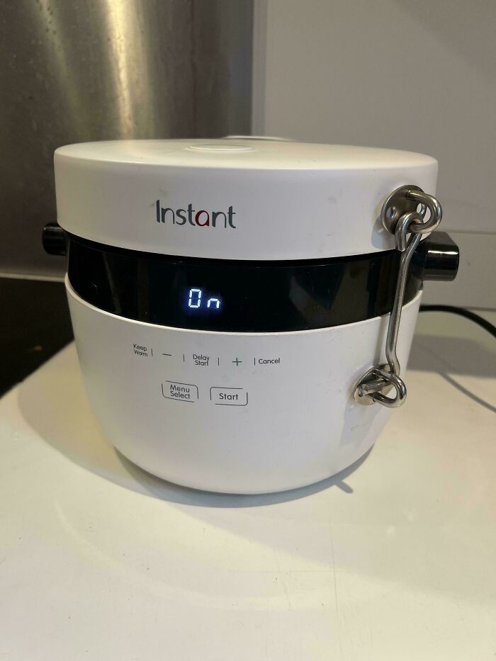 Instant pot with lid secured by a metal latch, showing a creative and technically works solution to keep it closed.