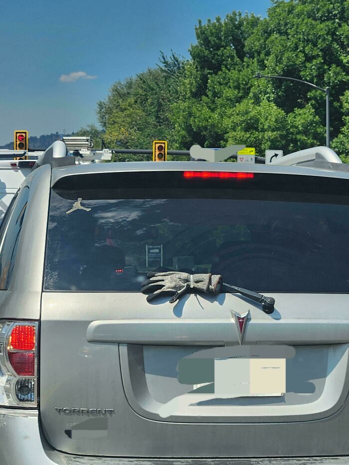Silver Pontiac Torrent SUV with gloves tied to rear windshield wiper, showing a technically works solution to a problem on the road.