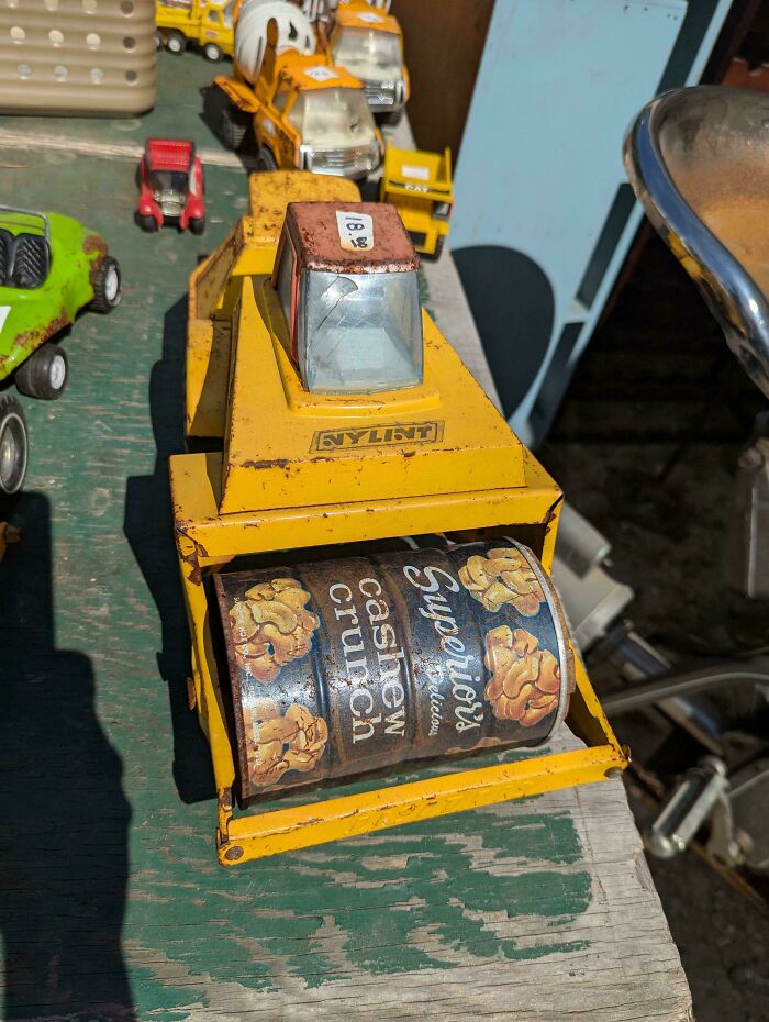 Yellow toy construction vehicle with a cashew crunch can used as a roller, a technically works funny solution to a problem.