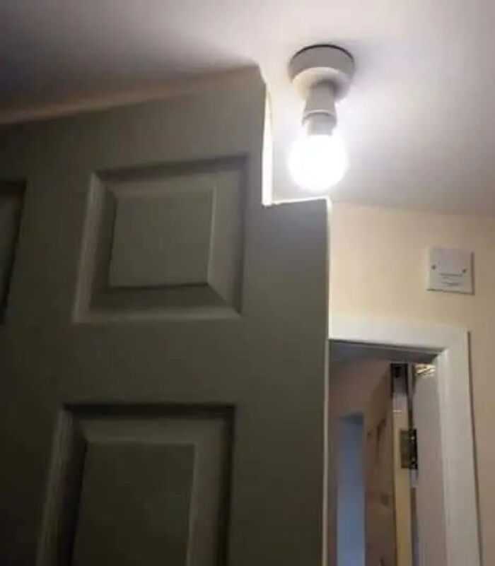 Door cut to fit around a ceiling light fixture, showing a technically dumb but functional solution.