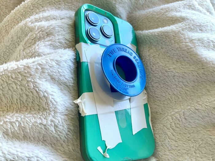 Smart yet dumb solution with a phone glued to a blue spool using tape, demonstrating a technically works fix.