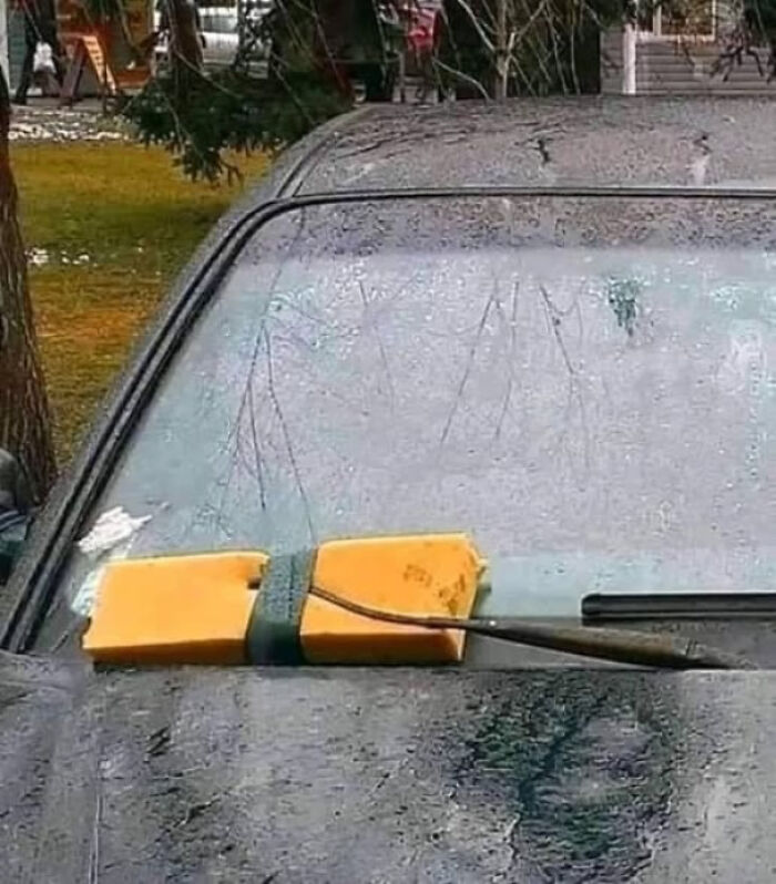 Car windshield cleaned using a large sponge strapped to the wiper arm in a technically works solution.