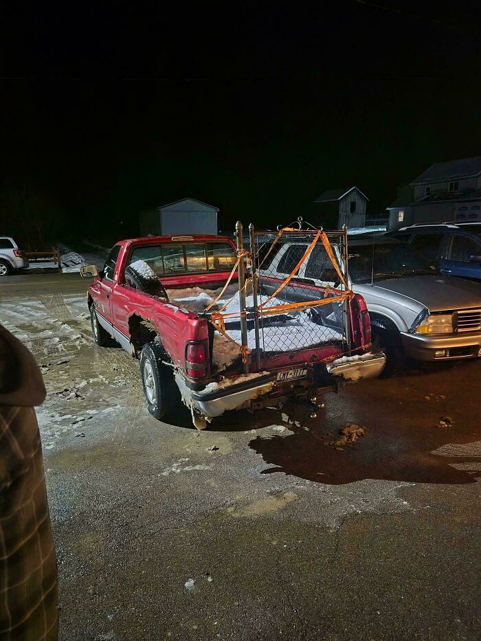Red truck with a makeshift fence attached to the bed, a technically works but hilariously dumb solution to a problem.
