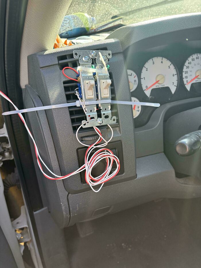 Car dashboard with a zip-tied switch panel and loose wiring as a technically works but unconventional solution.