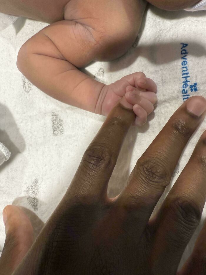 Close-up of a newborn's tiny hand holding an adult finger, symbolizing the bond between dads and their children.