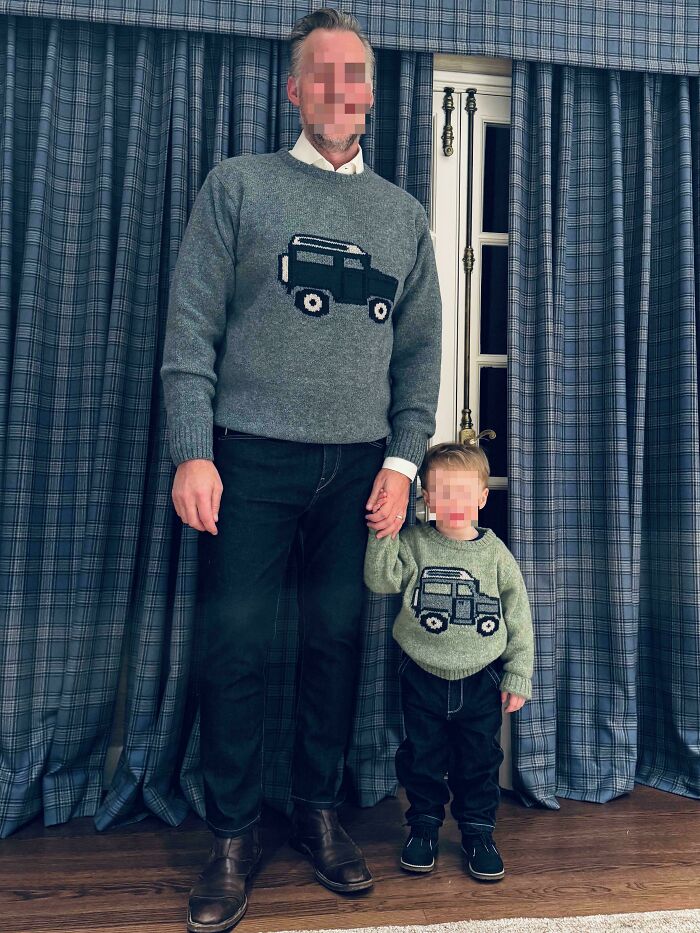 A dad and his child in matching truck sweaters, standing by blue plaid curtains. Celebrating dads.