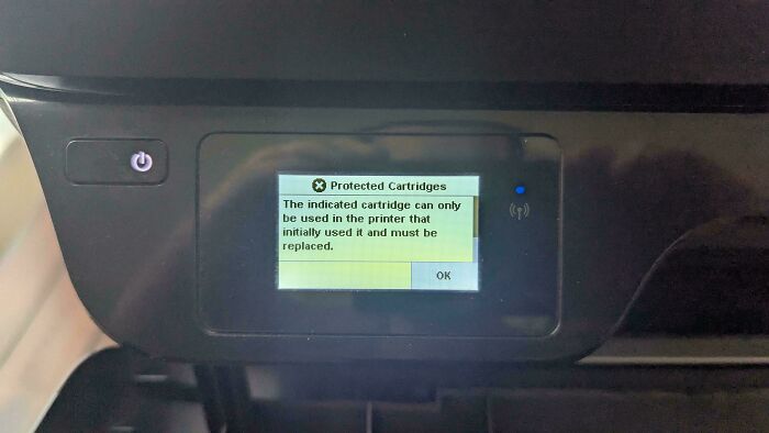 Car dashboard screen showing printer cartridge error, illustrating design that feels genuinely evil with unexpected advertisements.