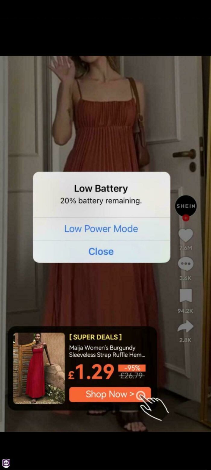 A woman in a burgundy dress with a low battery phone ad overlay showing deceptive advertisement design.
