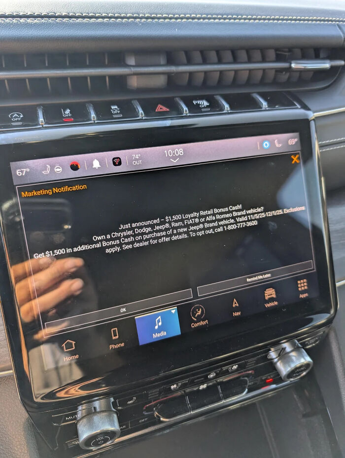 Car dashboard touchscreen displaying an unwanted marketing notification promoting loyalty retail bonus cash offers.
