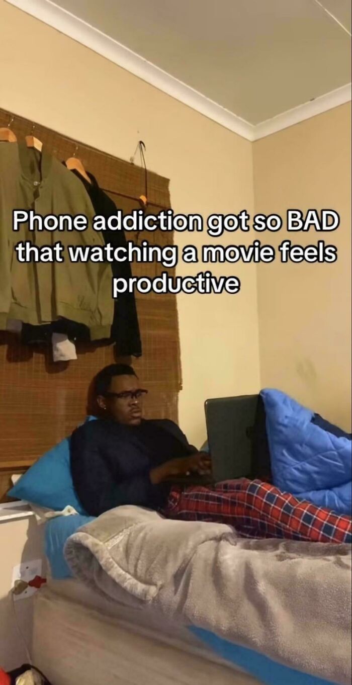 Person in pajamas on a bed with a laptop, illustrating relatable meme about phone a*******n and everyday life struggles.