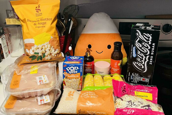 Assorted groceries including popcorn, chicken, rice, corn, and soda showcasing grocery costs where they live