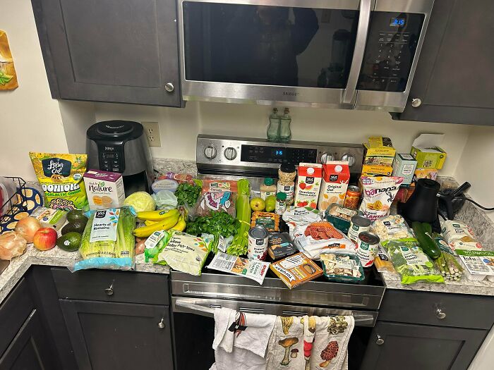Groceries spread on kitchen counter showing diverse fresh produce and packaged items highlighting grocery cost differences.