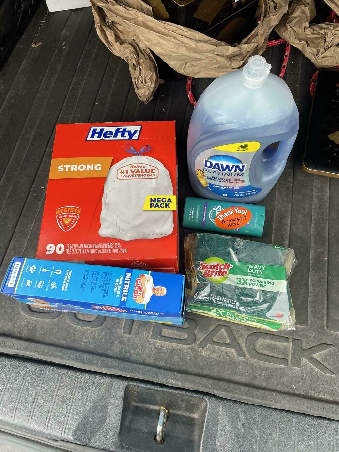 Cleaning supplies including Hefty bags, Dawn detergent, gloves, and scrubbers displayed in a photo about grocery costs.