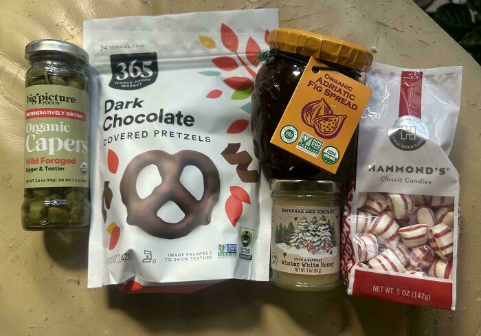 Various grocery items including organic capers, dark chocolate pretzels, fig spread, honey, and candies, showing grocery costs.