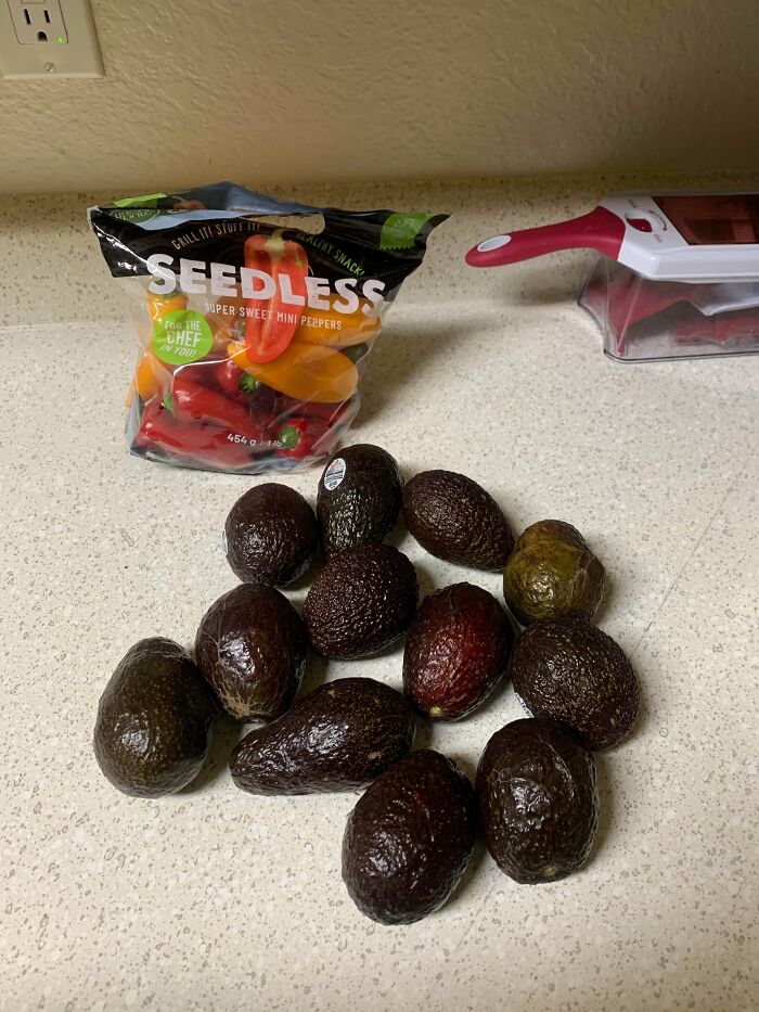 Bag of mini sweet peppers and a dozen avocados on a kitchen counter showing grocery cost where they live.