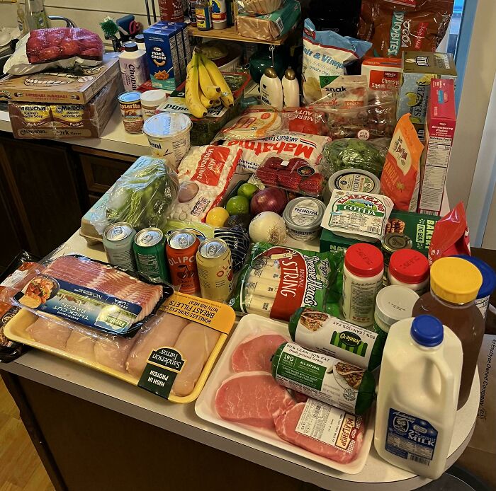 Groceries spread on a kitchen counter showing a variety of food items depicting grocery costs where people live.
