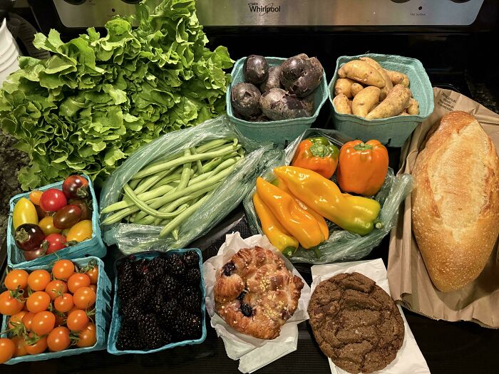 Fresh vegetables, baked goods, and fruits displayed on a kitchen counter showing grocery cost comparison locally.