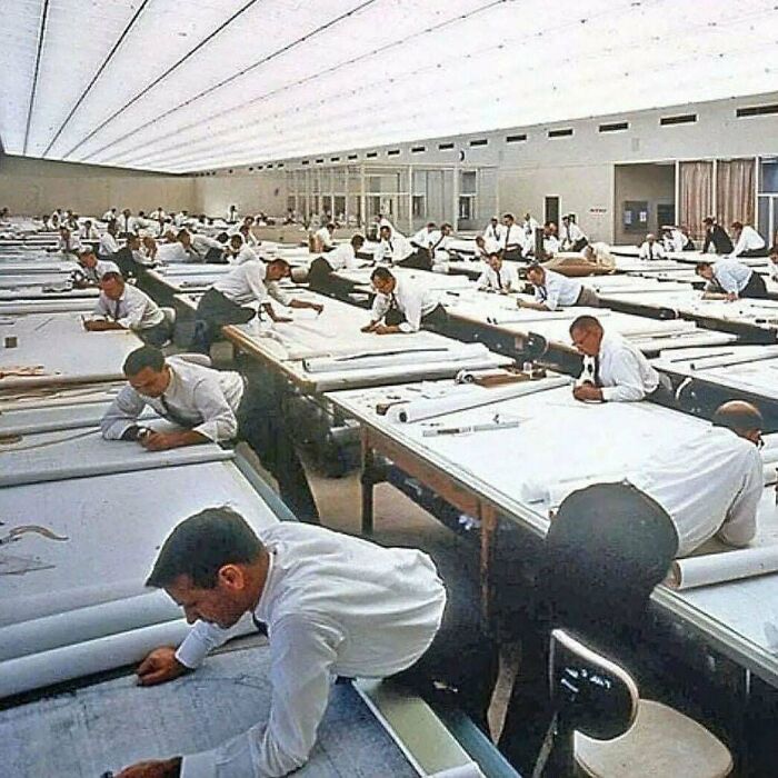 Interesting photo of many engineers working diligently at drafting tables in a large office.