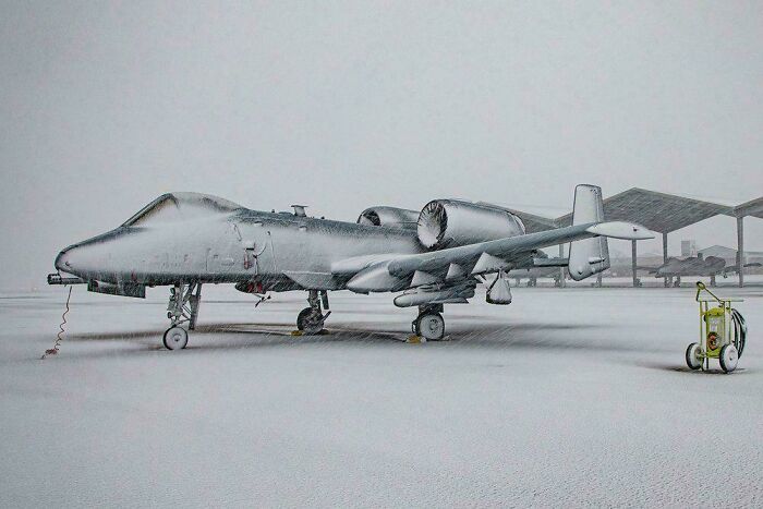Interesting photo of an A-10 Thunderbolt II aircraft covered in snow on an airfield.