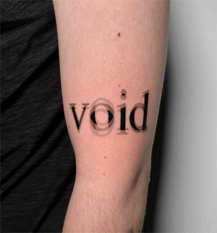 An interesting photo of a unique forearm tattoo that spells out the word 'void' with a blurry, overlapping effect.