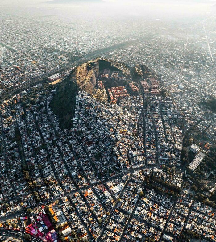 An aerial view of a densely populated city surrounding a large hill, an interesting photo.