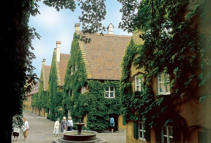 Interesting architecture with ivy-covered houses and a fountain, showcasing a charming European street.