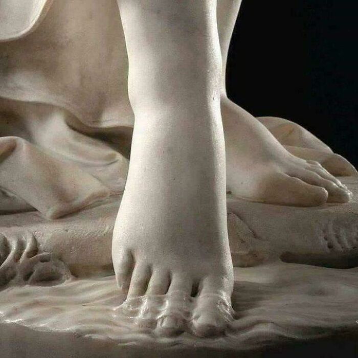 A close-up of a marble statue showing incredibly detailed feet, an interesting artistic photo.
