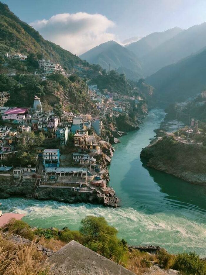 A vibrant river flowing through a mountain valley, with colorful houses nestled on the slopes, an interesting photo of a scenic landscape.
