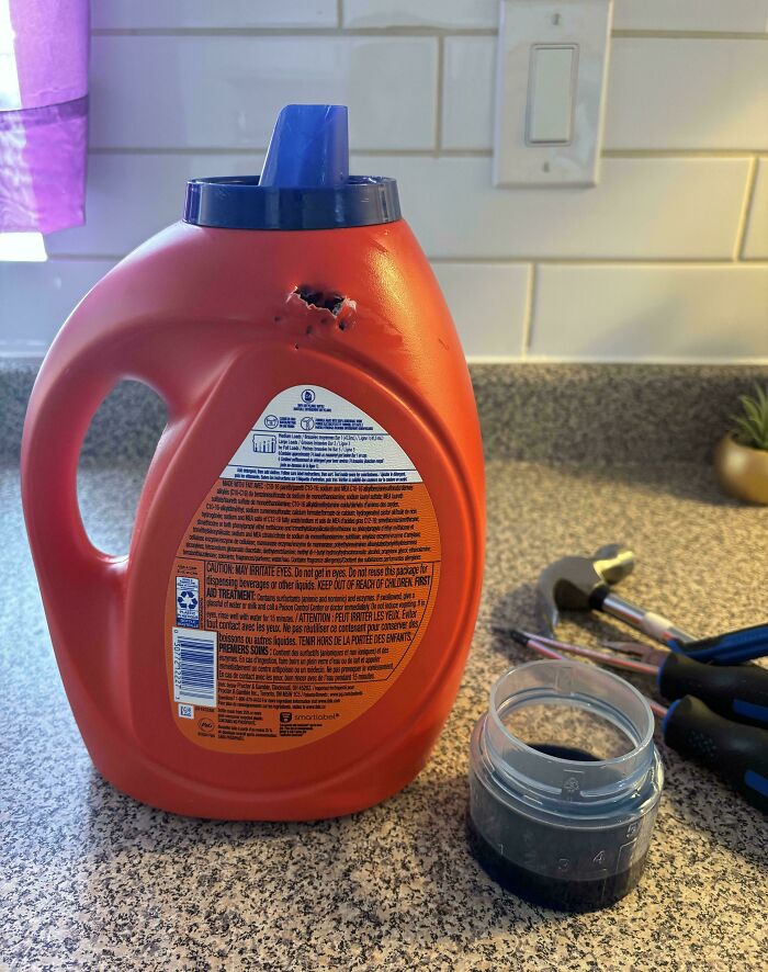 A Tide detergent bottle with holes, next to tools and a measuring cup, showcasing frugal tips for the economy.