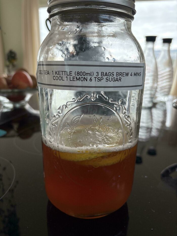 A mason jar with iced tea, lemon slices, and a recipe label on a kitchen counter. Frugal tips for a whole new world.