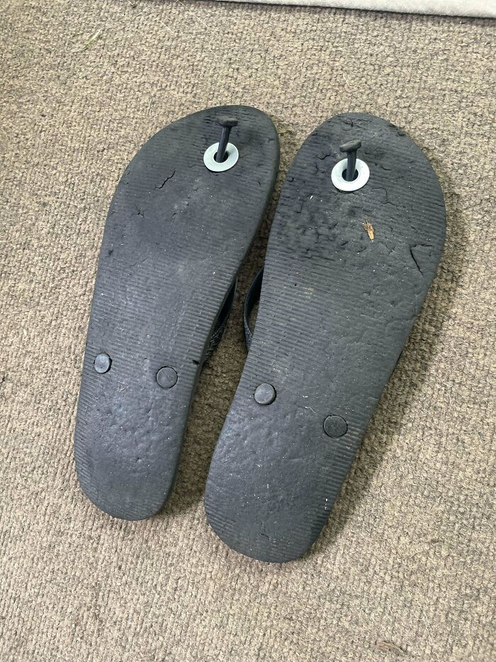 Worn black flip-flops on carpet, showing a DIY repair with a nail and washer. A frugal tip for this economy.