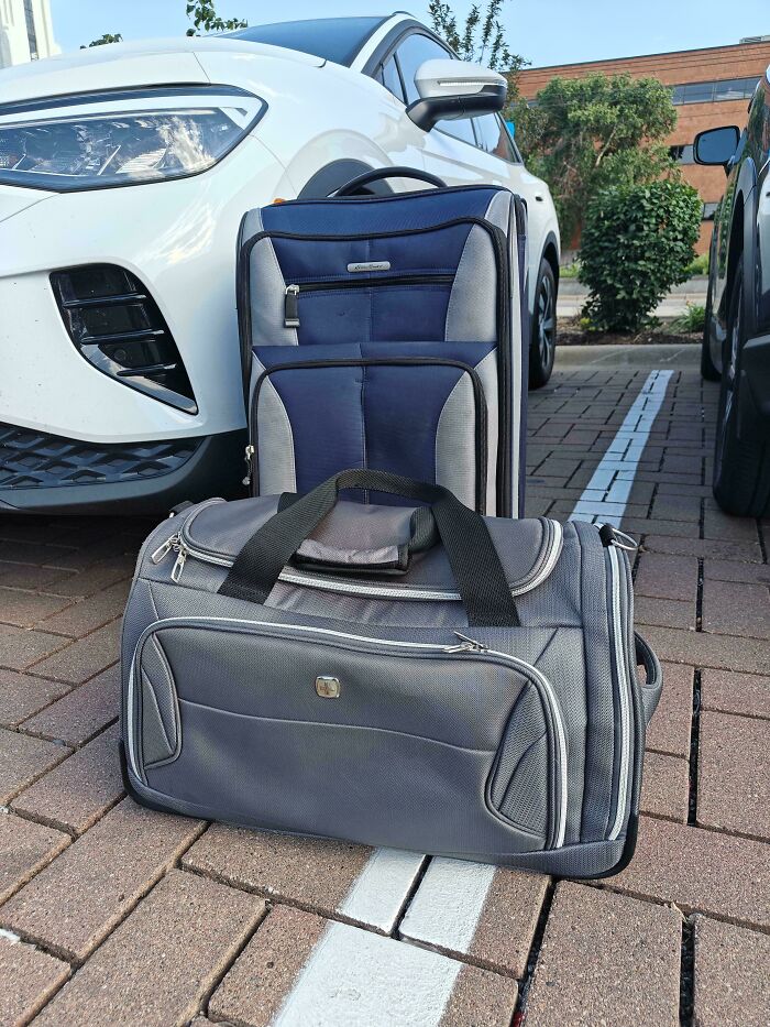 Two suitcases, one blue and one gray, in front of a white car, illustrating frugal tips for traveling in this economy.
