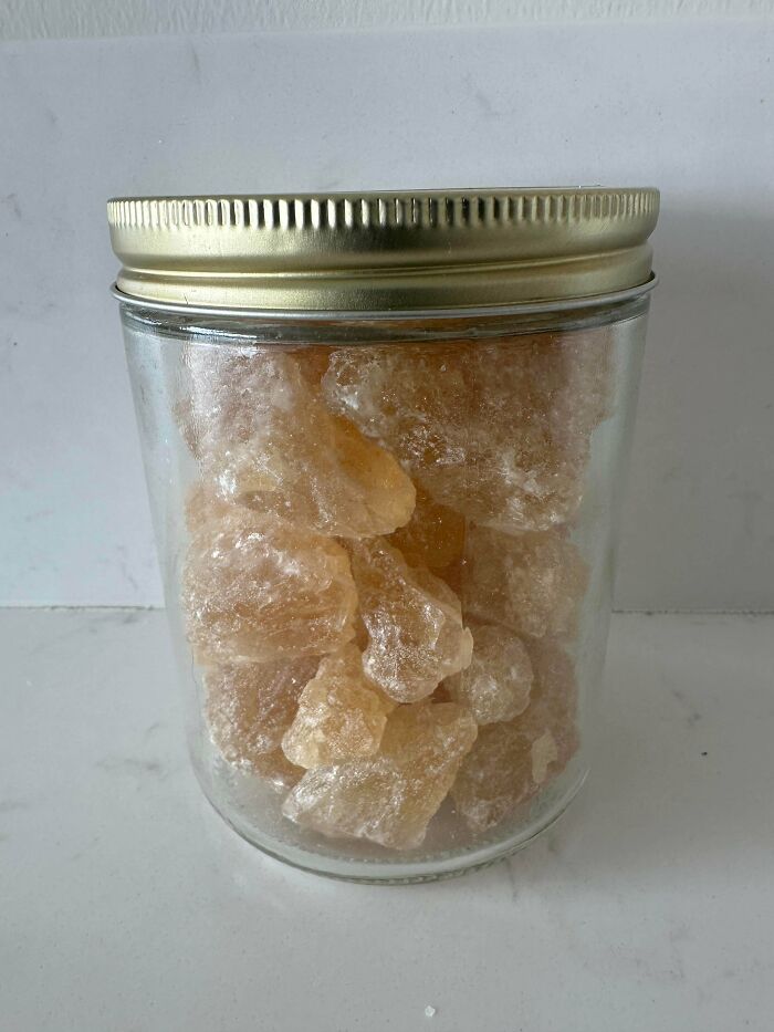 A clear glass jar filled with translucent golden rock candy, sealed with a brass lid. Frugal tips for a whole new world.