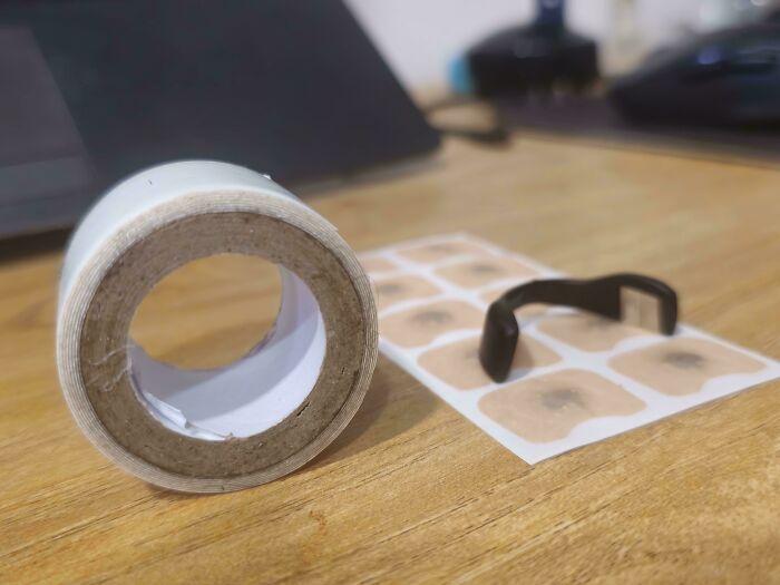 Frugal tips shown with a roll of white tape and adhesive patches, plus a black clip, on a wooden surface.
