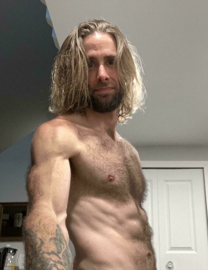 Muscular man with amazing long hair and a beard, looking directly at the viewer.