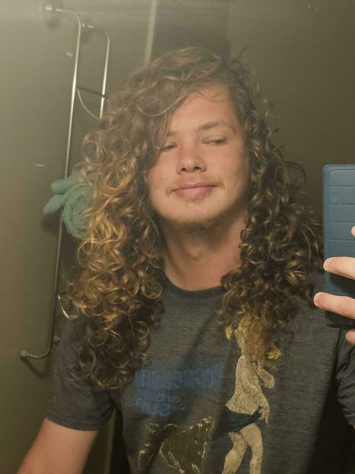 Young man with amazing long hair and a light beard, looking at the camera.