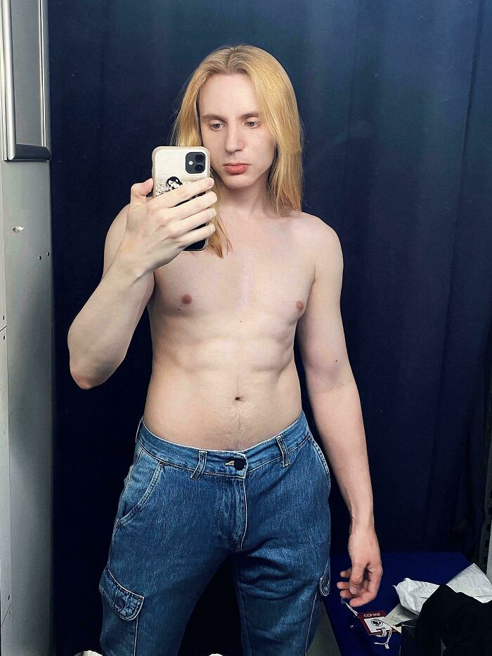 Man with amazing long hair, shirtless and wearing jeans, taking a mirror selfie.