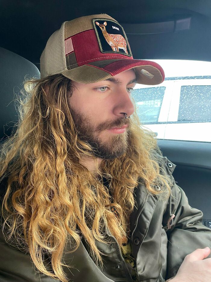 Man with amazing long hair and a beard, wearing a hat, looking to the side.